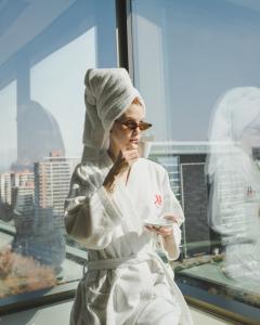 Una donna vestita di bianco davanti a una finestra di Santiago Marriott Hotel a Santiago