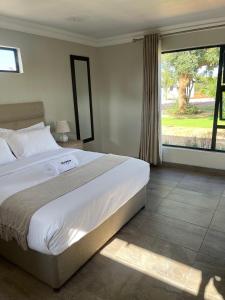 a bedroom with a large bed and a large window at Bluewave Farm Villa in Louis Trichardt