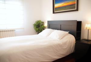 uma cama branca num quarto com uma fotografia na parede em Villa La Perla de Sonabia em Oriñón