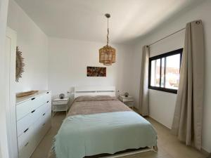 a white bedroom with a bed and a window at Casa Monte y Mar in Morro del Jable