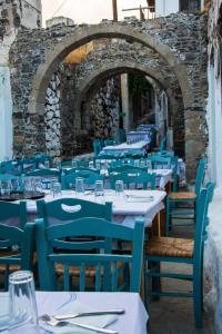un restaurante al aire libre con mesas y sillas azules en Kisiris House, en Mandrákion
