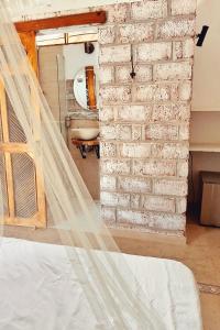 a bedroom with a brick wall next to a bed at Posada Gallinas in Palomino