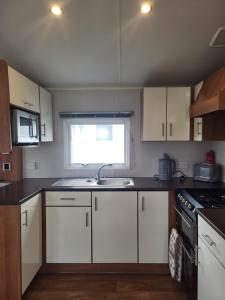 uma cozinha com armários brancos, um lavatório e uma janela em Beach View em Whitstable