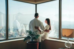 Un uomo e una donna in piedi davanti a una finestra di Santiago Marriott Hotel a Santiago