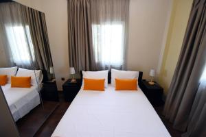 two beds in a hotel room with orange pillows at Potamos Studios by GERANI in Órmos