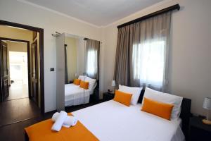 a bedroom with two beds with orange and white pillows at Potamos Studios by GERANI in Órmos