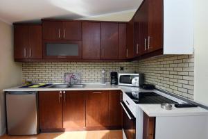 a kitchen with wooden cabinets and a sink and a microwave at Potamos Studios by GERANI in Órmos