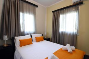 a bedroom with a large white bed with orange pillows at Potamos Studios by GERANI in Órmos