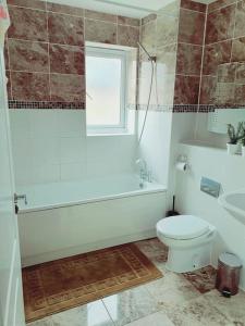 a bathroom with a toilet and a tub and a sink at Spacious and Tastefully Decorated Town House In Lakeside West Thurrock Grays in West Thurrock