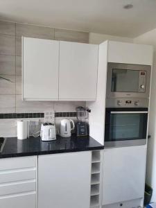 cocina con armarios blancos y microondas en Spacious and Tastefully Decorated Town House In Lakeside West Thurrock Grays, en West Thurrock