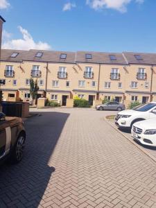 a large building with cars parked in a parking lot at Spacious and Tastefully Decorated Town House In Lakeside West Thurrock Grays in West Thurrock