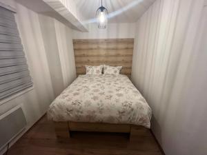 a small bedroom with a bed with a wooden headboard at Apartmani NIX VIR in Jahorina