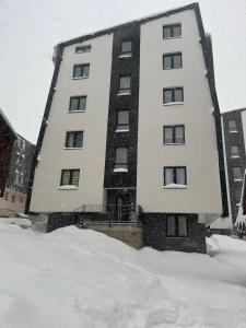 a building with snow in front of it at Apartmani NIX VIR in Jahorina
