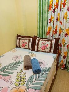 a bedroom with a bed with a floral bedspread and pillows at Aquing's Place in El Nido