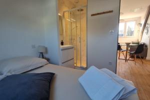 Schlafzimmer mit einem weißen Bett und einer Glasdusche in der Unterkunft Le Jaures 6 - T2 - Dernier Etage in Hennebont