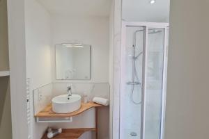 een witte badkamer met een wastafel en een douche bij Le Jaures 2 - T2 - RDC in Hennebont