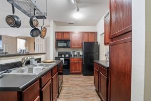 a kitchen with wooden cabinets and a black refrigerator at HEIRS VENTURES : Patriot . Near Civic Center . Museum . OKC Thunder Arena . With Washer and Dryer in Oklahoma City
