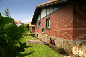 a red brick house with a stone wall at Villa La Perla de Sonabia in Oriñón