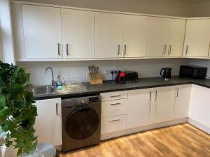 a kitchen with white cabinets and a dishwasher at The Cosy House in Hugglescote