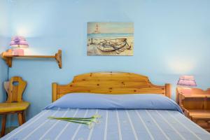 a blue bedroom with a bed with a wooden head board at Residence Asfodeli E4 in San Teodoro