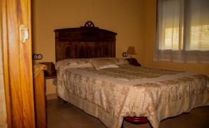 a bedroom with a bed with a wooden headboard at CASA RURAL EL RONDILLO in Navaconcejo