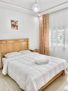 un grande letto bianco in una camera da letto con finestra di Cozy duplex a Rabat