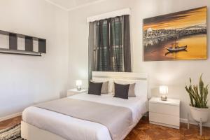 a white bedroom with a bed and a painting on the wall at Home Away From Home in Caniçal