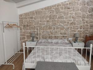 Cama blanca en habitación con pared de piedra en Appartamenti Mascagni en Sannicandro di Bari