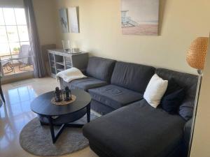 ein Wohnzimmer mit Sofa und Tisch in der Unterkunft Lägenhet högst upp, med pool och utsikt över havet in San Luis de Sabinillas
