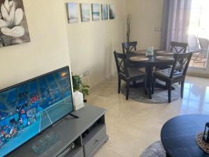 ein Wohnzimmer mit einem TV und einem Esstisch in der Unterkunft Lägenhet högst upp, med pool och utsikt över havet in San Luis de Sabinillas