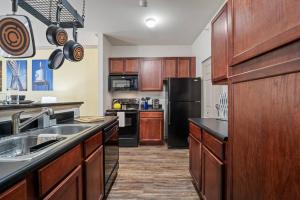 a kitchen with wooden cabinets and a black refrigerator at HEIRS VENTURES: Midtown . Near Hospitals . Pets OK* . W/D . 55” TV in Oklahoma City