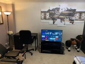 a living room with a television and a desk with a chair at Thames River Side Townhouse in Thamesmead