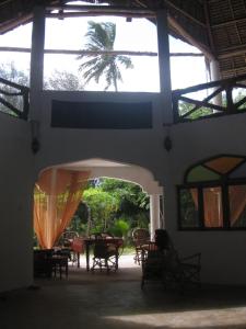 una habitación con mesas, sillas y una palmera en Casa Umoja, en Nungwi