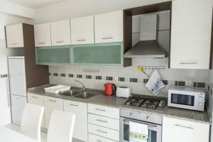 cocina con armarios blancos, fregadero y microondas en 3 bedroom apt, Exterior POOL , Cidadela - LCGR, en Praia