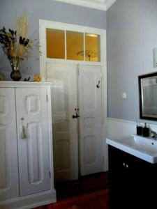 W białej łazience znajduje się umywalka i lustro. w obiekcie B&B Quarto Rosa Estilo Romântico 