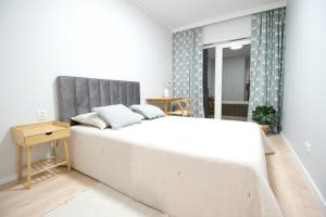 a bedroom with a large white bed with a gray headboard at Hygge Malta - NOWY apartament in Poznań