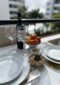 a table with plates and glasses and a bottle of wine at Lagos Apartment Ocean View in Lagos
