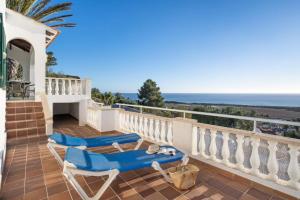 a balcony with two blue chairs and the ocean at Villa Atalis in Son Bou