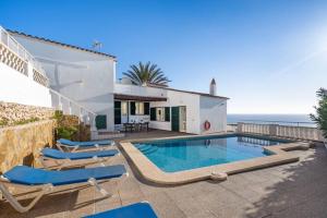 a house with a swimming pool with chairs and the ocean at Villa Atalis in Son Bou
