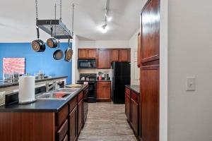 uma cozinha com armários de madeira e um balcão preto em HEIRS VENTURES: Fantasy . Near DT . WiFi . King Bed . W/D . 55” TV em Oklahoma City