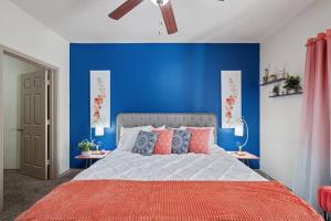 een slaapkamer met een blauwe muur en een bed met kussens bij HEIRS VENTURES: Fantasy . Near DT . WiFi . King Bed . W/D . 55” TV in Oklahoma City