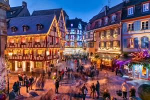 un groupe de personnes se promenant dans une rue avec des bâtiments dans l'établissement La forêt Enchantée - Cozy Immo, à Orschwiller