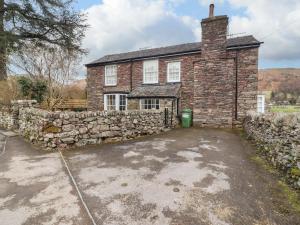 uma antiga casa de tijolos com uma parede de pedra em Pavement End Cottage em Grasmere