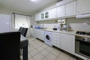 a kitchen with white cabinets and a washing machine at Aveiro Cozy Apartment in Eixo