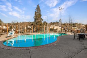 a swimming pool at a resort with a table and a tree at Heritage Inn - Yosemite/Sonora in Sonora