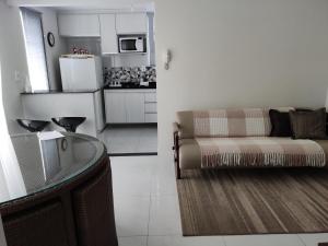 a living room with a couch and a kitchen at Apartamento Ar condicionado, varanda, 2 vagas garagem in Muriaé