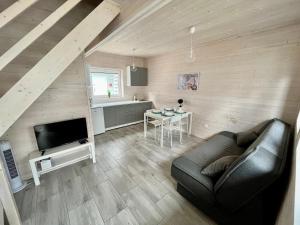 ein Wohnzimmer mit einem Sofa, einem TV und einem Tisch in der Unterkunft Domki Kalmar Sarbinowo in Sarbinowo
