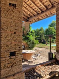 un patio al aire libre con una mesa y una pared de piedra en La roul'hôte dépote, en Monbéqui