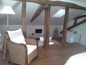 a room with a bed and a chair and a tv at Maison d'hôtes Brameloup Jardin Ovale in Coudures