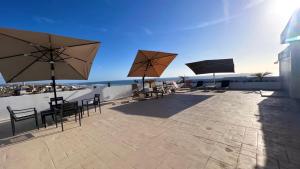 a patio with tables and chairs and umbrellas at Luxury Condo Downtown Rosarito in Rosarito